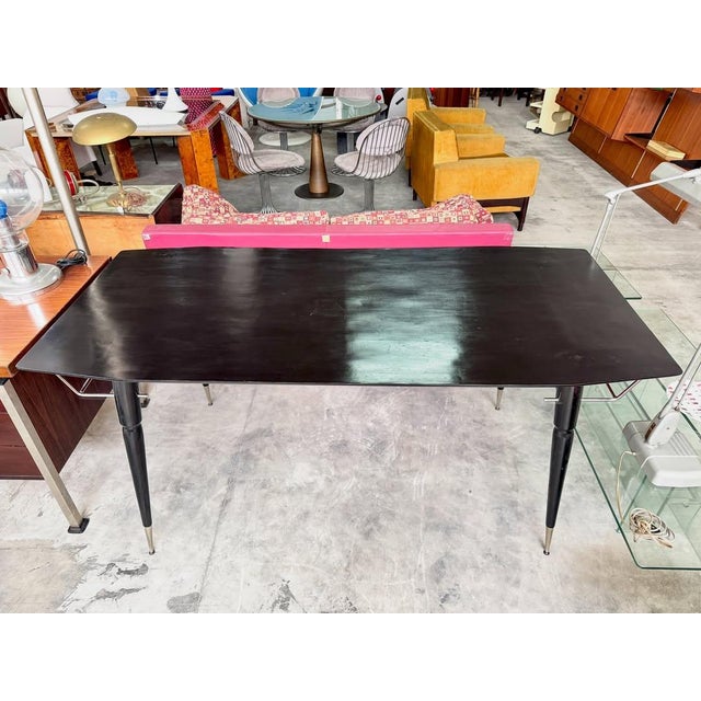 Black lacquered wood dining table with conical legs and chrome details, 1960s. rectangular top in matte black lacquered...