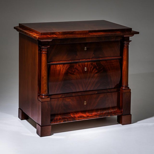 Three-drawer Biedermeier chest of drawers with book-matched mahogany veneer and flanking columns raised on square legs....