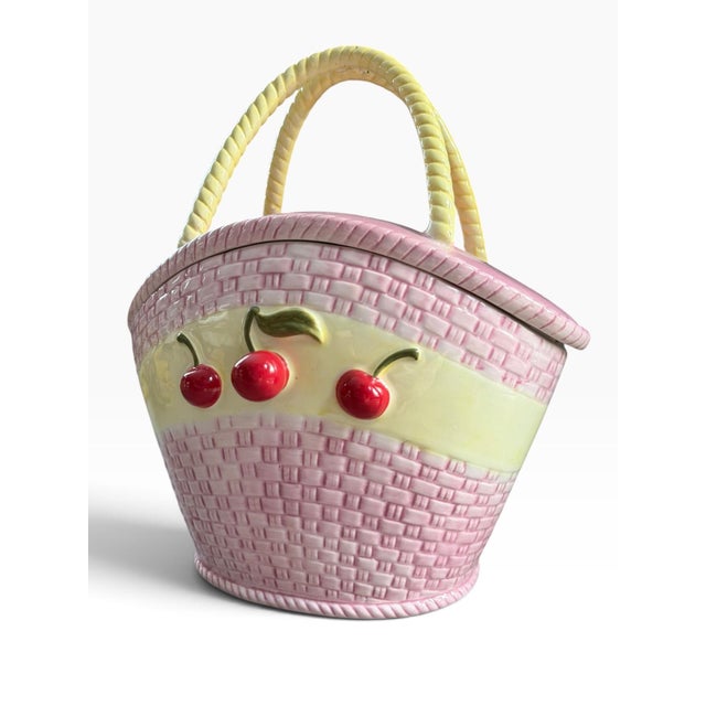 Charming decorative ceramic cookie jar designed in the form of a woven picnic basket, featuring a sweet pastel pink basket...