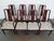 A striking vintage set of eight dining chairs featuring elegant Asian-style design elements, tall sculptural backs, and a...