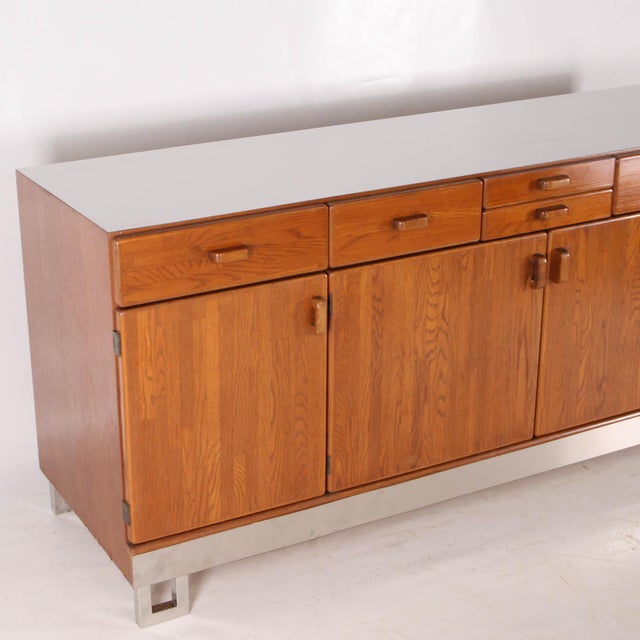 Rare vintage sideboard in oak and brushed aluminum. Featuring six drawers and four doors concealing interior shelves, this...