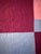 A large Amish quilt of center bars pattern made from a striking combination of contrasting colors: light blue, maroon red...