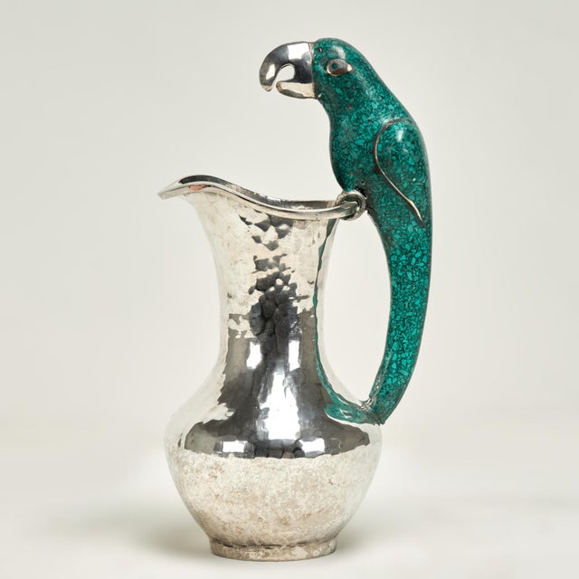 Standout vintage pitcher handcrafted in silver plate on hammered copper featuring a stone clad parrot as a handle....