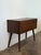 This compact entry table features a clean silhouette elevated by slender tapered legs. A drop-down door reveals a spacious...