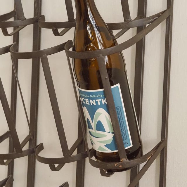 Metal wall shelf for nine wine bottles, with a semi-circular top and embossed grape motif. The open design combines...