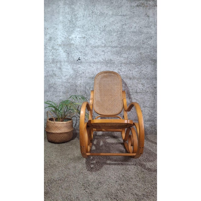 Steam-bent beechwood rocking chair in the pure Thonet tradition. The seat and elongated oval back are upholstered in fine...