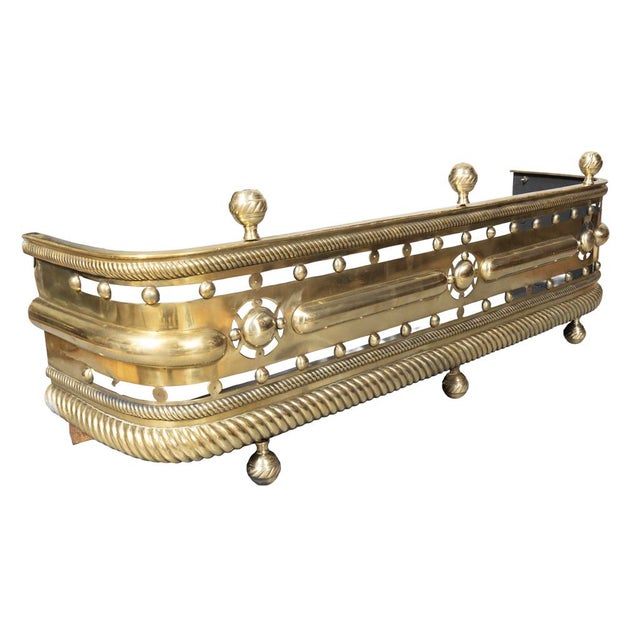 Regency brass fire fender. With three ball finials over a pierced body repeating spheres. Rope form lower edge and ball feet.