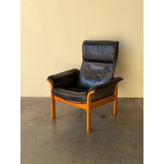 Beautiful vintage Swedish lounge armchair by Göte Möbler, featuring supple black leather upholstery paired with a solid...