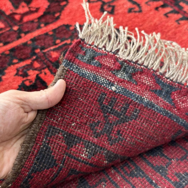 Vintage Afghan Bokhara tribal rug featuring three bold stacked Fil-Pa (elephant's foot) octagonal guls in deep oxblood red...