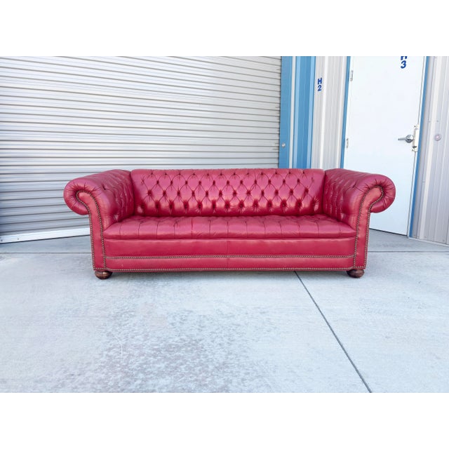 This iconic Chesterfield sofa makes a bold, luxurious statement with its vibrant crimson red leather upholstery and...