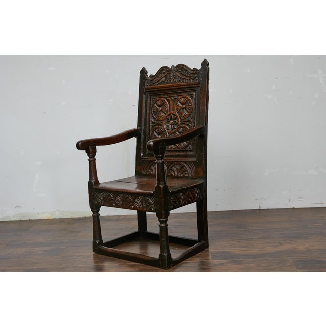 An English Jacobean oak high back armchair from the late 17th century with carved décor. This English Jacobean period oak...