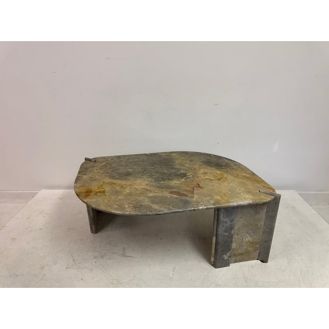 A marble coffee table from the 1980s. Eye shaped top that is predominantly grey with flashes of other colours. Fluted legs...