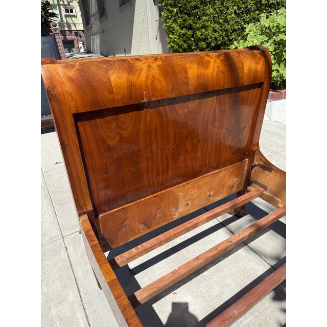 A beautifully proportioned antique American Empire sleigh-form daybed, crafted in richly figured flame mahogany veneer and...