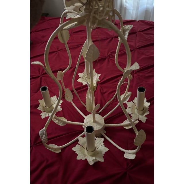 White iron Wendy Bellissimo Teaberry 22in chandelier with 4 candle style lights and leaf/flower accents. Includes original...