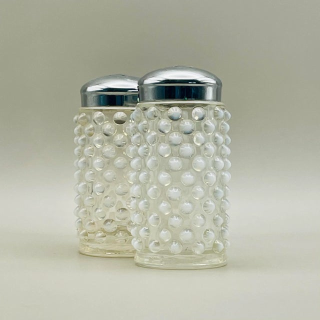 A pair of translucent white tipped hobnail glass salt and pepper shakers with chrome tops made by the Fenton Glass...