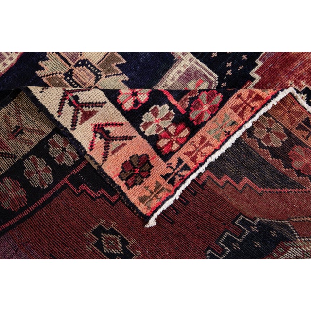 A hand-knotted vintage Azeri runner with an artistic design on a burgundy field. Multi-color accents throughout the piece....