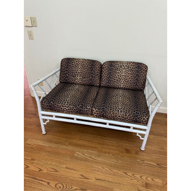 Chic vintage faux bamboo loveseat with a white lacquer finish, featuring classic Chinoiserie fretwork arms and back. The...