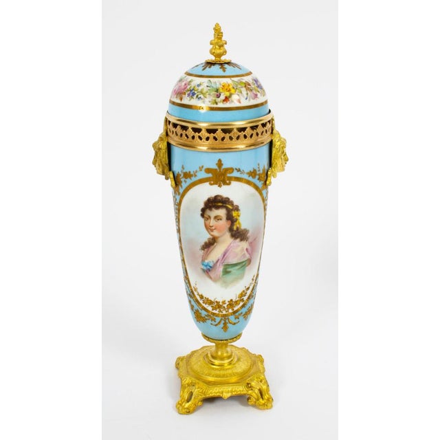 This is a beautiful antique pair of french sevres porcelain twin masque head handled lidded urns with dome lids, in the...
