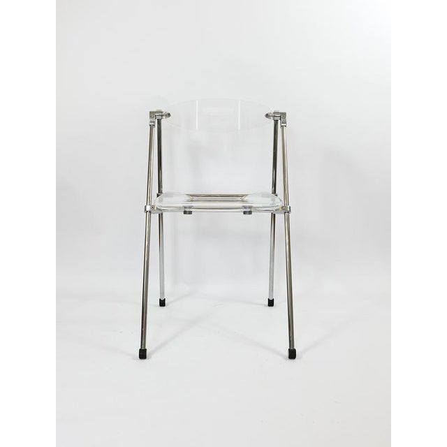A stylish postmodern foldable "ghost" chair with a chrome frame and a clear acrylic glass acrylic acrylic glass seat and...