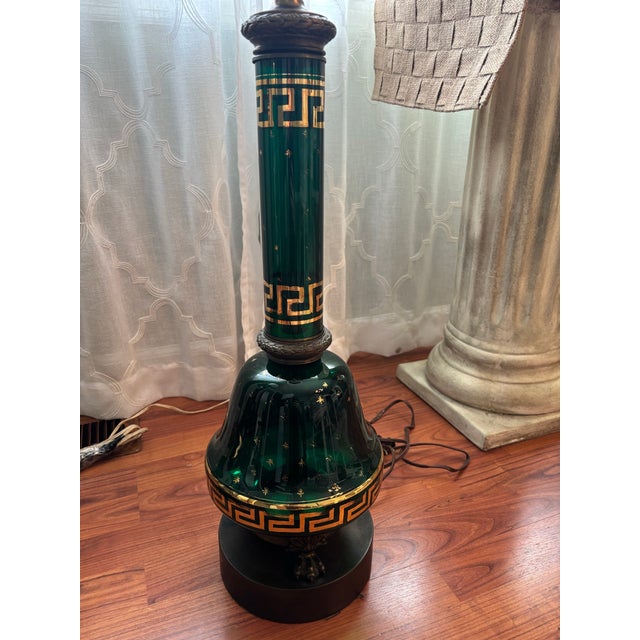 Pair of 1960’s Hollywood Regency style green glass lamps with gilt Greek key and star decorations. The bases are made of...