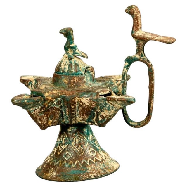 A rare and highly evocative medieval Islamic copper-alloy oil lamp, attributed to the 14th century, distinguished by its...