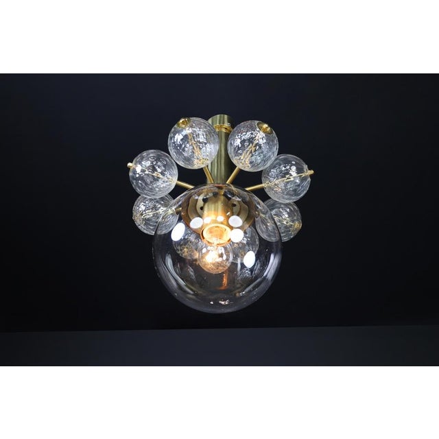 Mid-20th century chandelier with brass fixture and hand-blown glass globes an exquisite example of mid-century modern...