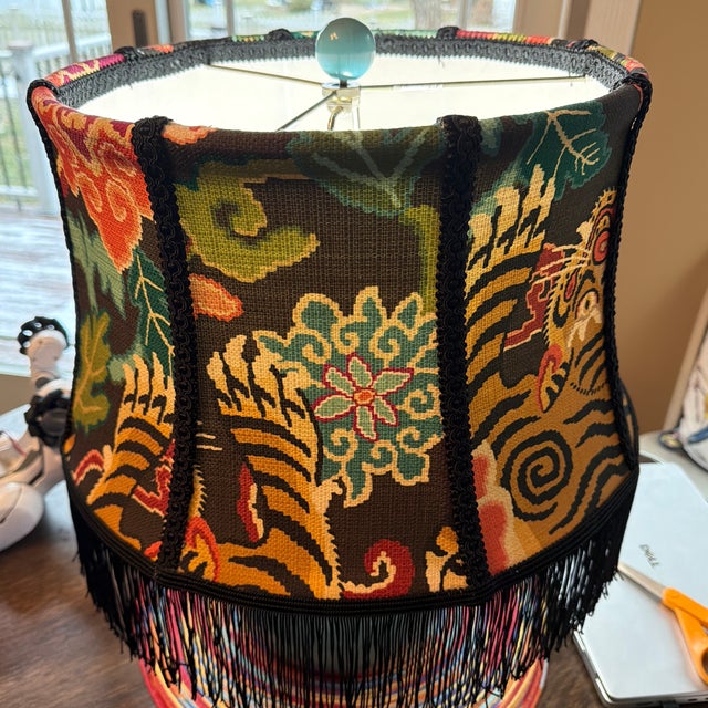 A richly patterned vintage lampshade featuring a bold tiger motif surrounded by vibrant florals, rendered in saturated...