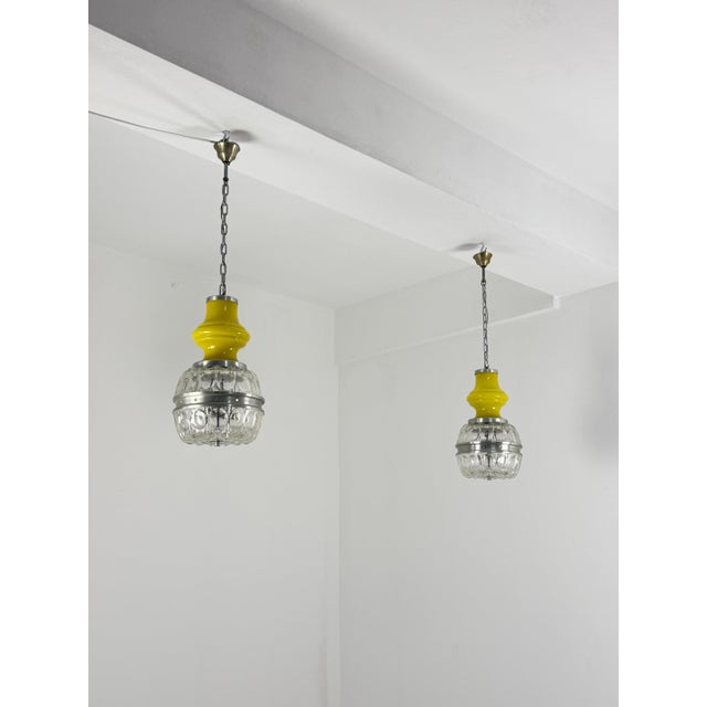 Set of two Space Age pendant lamps in yellow Murano glass, worked, 1970s Intact and in good condition. Each lamp has two...