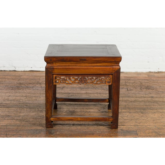 A Chinese late Qing Dynasty period side table from the early 20th century with carved apron and scrolling feet. Infusing...