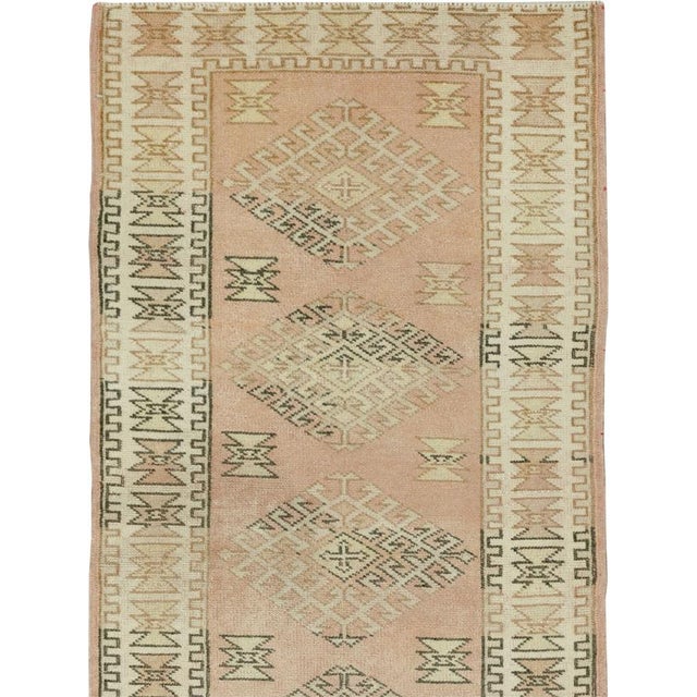 This mid-20th-century Turkish Anatolian runner presents a disciplined procession of large diamond medallions arranged...