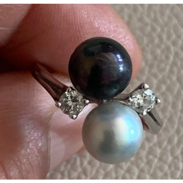 This elegant vintage ring features two lustrous freshwater pearls, one black and one white, set in luxurious 14k white...