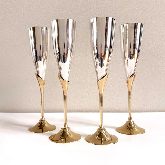 A sculptural set of vintage champagne flutes with polished silver-tone vessels and slender brass stems. Refined and...