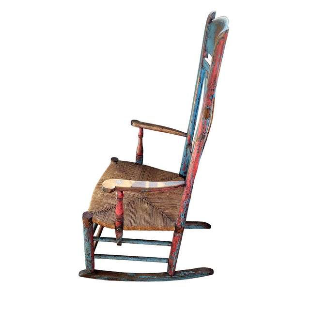 A Beautiful Painted Rocking Chair featuring 4 slat back finials, shaped arm rest and rush seat. Retaining a beautiful old...