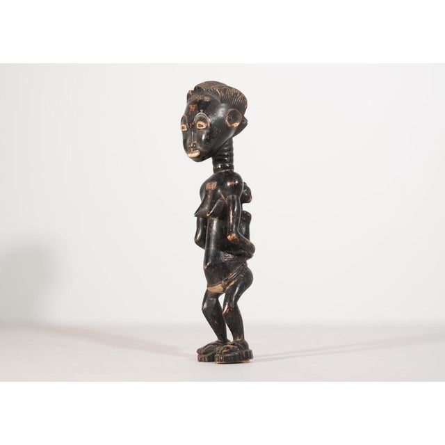 A captivating hand-carved wooden figurine representing traditional African tribal art, likely originating from the first...