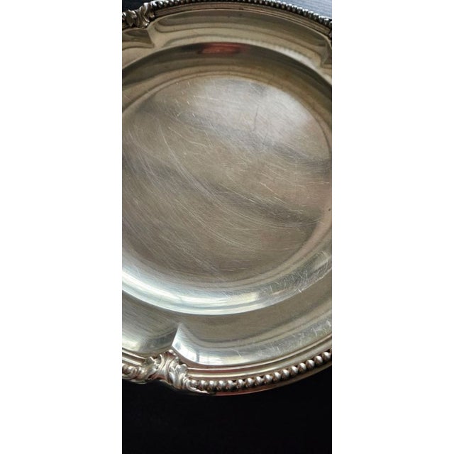 2 round dishes in a scalloped shape bordered with a beaded pattern alternating with acanthus leaves. They are stamped with...