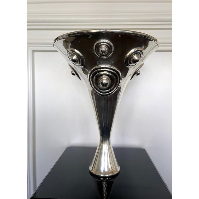 A large sterling silver vessel in an asymmetrical hour-glass vase form with a larger upper conical body balanced on a much...