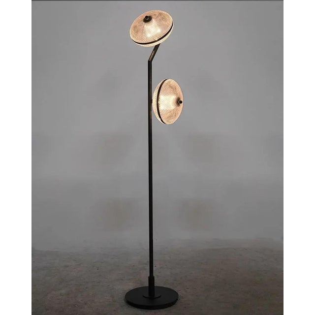 An appealing mix of industrial studio lighting and futurism, the Gibson floor lamp features two enclosed, textured glass...