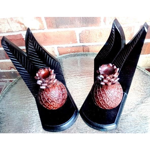 Each of this pretty pair of carved wood bookends has a rich, reddish-brown pineapple attached to a deep, dark brown base...