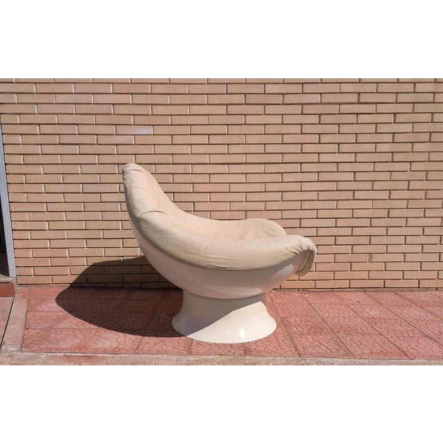 This vintage Space Age-style armchair features a sculptural egg-shaped shell in glossy, cream-white plastic, housing a...