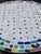 Beautiful round mosaic tile table featuring a vibrant multicolor and off white tiled top and durable black wrought-iron...