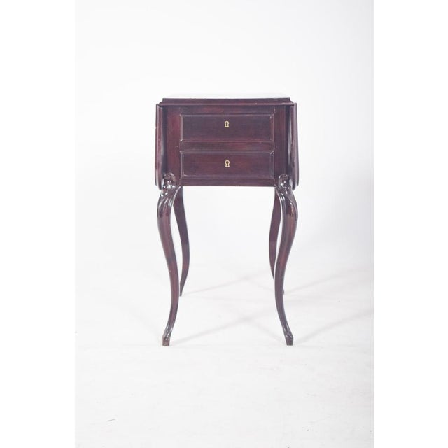 Potty table with flaps. In dark wood, with a folding top and two drawers at the front. The structure consists of four...