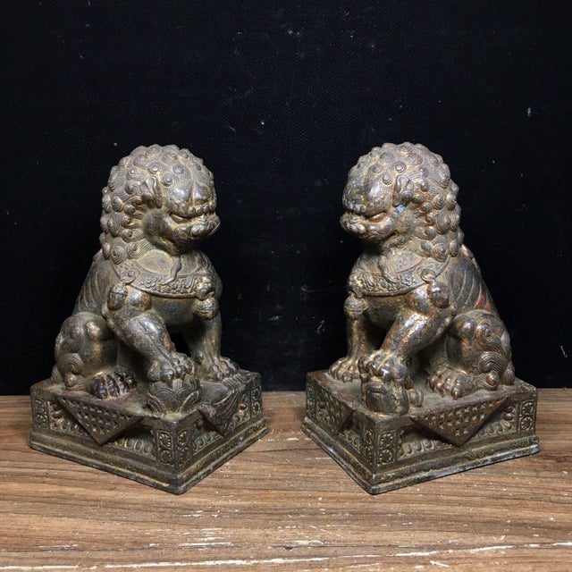 This is a striking pair of vintage bronze guardian lion statues, traditional symbols of protection and good fortune. The...