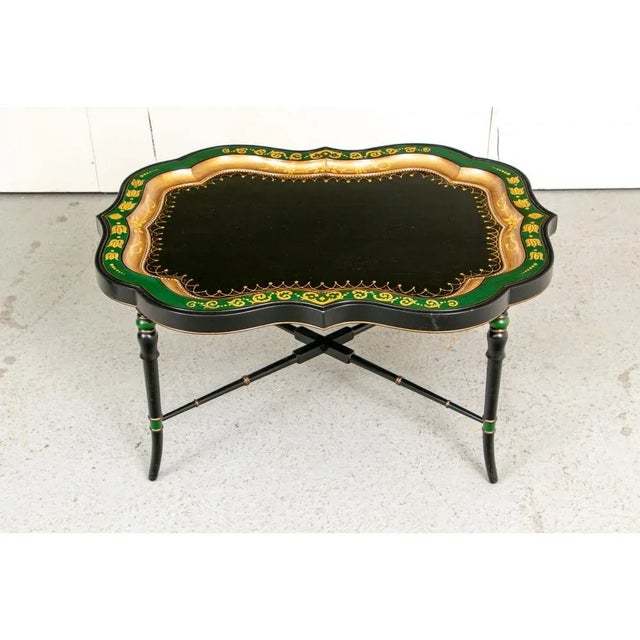 A well crafted carved, ebonized, and gilt serpentine tray table with beautifully painted accents and a detachable tray...