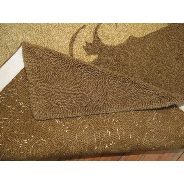 A large mid-20th century handwoven hooked rug featuring a oval floral palette in predominant soft brown. Other colors are...