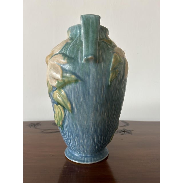 This is a painted ceramic vase produced by roseville in the usa: the clematis line was introduced by roseville pottery in...