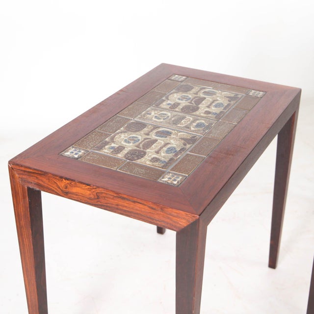 Rare set of three Danish coffee tables in rosewood and "Royal Copenhagen" ceramic tiles, circa 1970. The manufacturer's...
