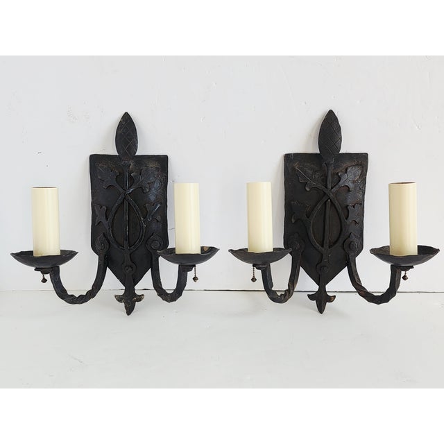 Antique early 20th century pair of Spanish Revival wrought iron wall sconces. The hand forged sconces feature a back...
