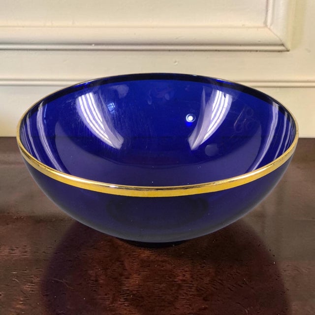 This vintage cobalt blue glass serving bowl features a gilded rim, adding a touch of elegance to any dining table or...