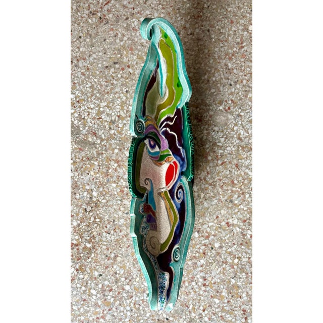 Its elongated, organic shape curves and twists with fluidity, evoking natural elements like leaves or waves. At the heart...