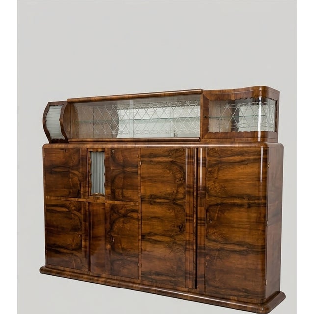 An impressive Art Deco sideboard and glass display cabinet, handcrafted in walnut veneer with a deep, lustrous finish. The...